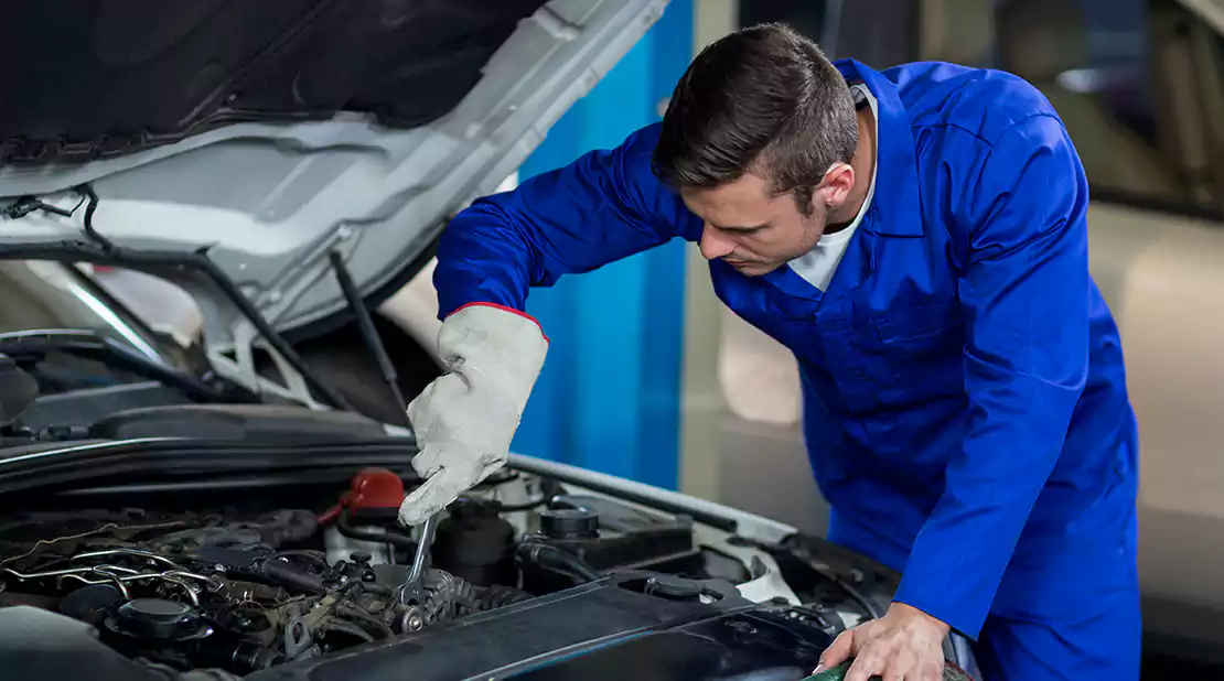 Car Mechanic looking into car's engine, doing car engine service